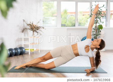 Experienced girl fitness club teacher performs side plank, vasishthasana Experienced girl fitness club teacher performs side plank, vasishthasana 107813908