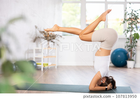 Experienced girl fitness club teacher performs feathered peacock asana, pincha mayurasana 107813950