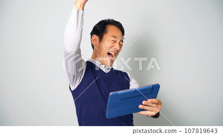 Middle-aged man gets excited looking at a tablet Middle-aged man gets excited looking at a tablet 107819643
