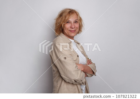 Cute successful mature woman with short blonde bob hair standing with arm crossed  107821322