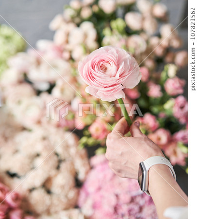 A woman takes a photo on her phone of flowers. Floral shop concept . Florist woman creates flower arrangement in a wicker basket. . Flowers delivery. A woman writes a video blog or online course A woman takes a photo on her phone of flowers. Floral shop concept . Florist woman creates flower arrangement in a wicker basket. . Flowers delivery. A woman writes a video blog or online course 107821562