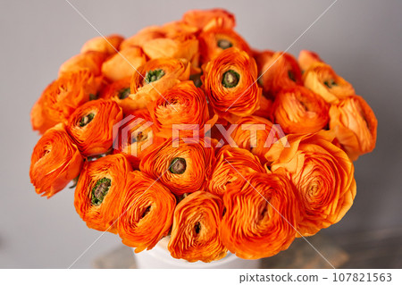 Persian buttercup. Bunch of orange ranunculus flowers on light gray background. Vase on vintage wooden table. Spring background, flower Wallpaper. Persian buttercup. Bunch of orange ranunculus flowers on light gray background. Vase on vintage wooden table. Spring background, flower Wallpaper. 107821563