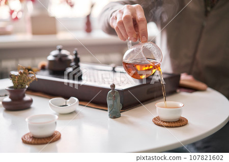 Tea master pours white tea to guests. Everything is ready for the tea ceremony. The ceremony is according to all the rules, but not in the classical style. Adapted to a modern apartment. 107821602