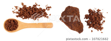 Dark muscovado sugar or Barbados sugar in wooden spoon isolated on white background. Top view. Flat lay 107821682