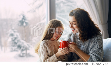 Mother and daughter enjoying winter nature in the  window 107821786