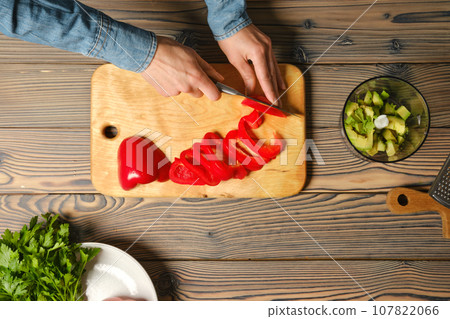 Top view of female hands slicing bell pepper Top view of female hands slicing bell pepper 107822066