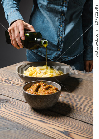 Unrecognizable woman pouring olive oil into plate with pasta Unrecognizable woman pouring olive oil into plate with pasta 107822098