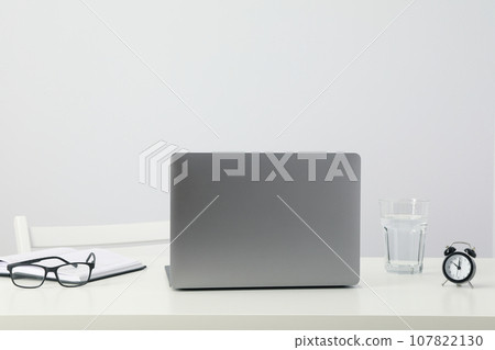 Laptop, glasses, glass and alarm clock on table on white background 107822130