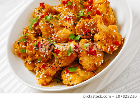 crispy orange cauliflower florets in white bowl 107822210