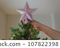 Preparing for the New Year. Hand decorating the Christmas tree with a festive star. 107822398