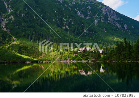 View on cabin in mountains with green forest. House for tourists in Tatra National Park near Morskie Oko or Eye Sea lake. Touristic place in Poland 107822983