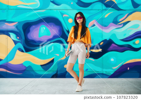 Female street artist standing near the wall with her paintings 107823320
