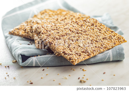 Knackebrot with sesame seeds. Wholegrain crispbread on napkin on kitchen table. Knackebrot with sesame seeds. Wholegrain crispbread on napkin on kitchen table. 107823963