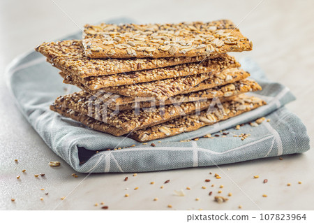 Knackebrot with sesame seeds. Wholegrain crispbread on napkin on kitchen table. Knackebrot with sesame seeds. Wholegrain crispbread on napkin on kitchen table. 107823964