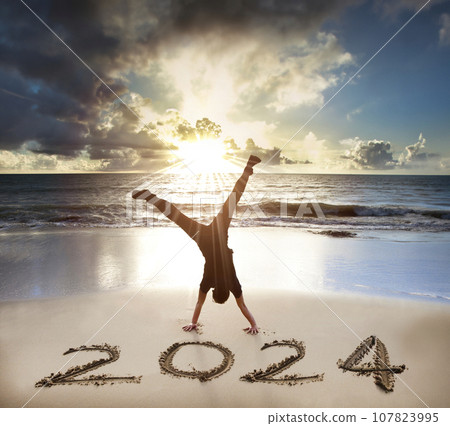Excited Young man handstand on the beach.happy new year 2024 concept 107823995