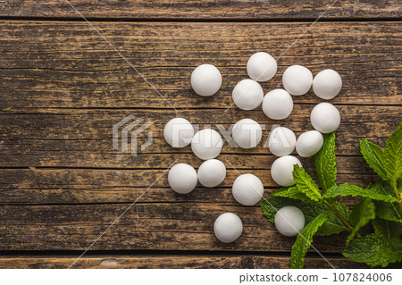Mint candies. Menthol bonbons and mint leaves on wooden table. Top view. 107824006