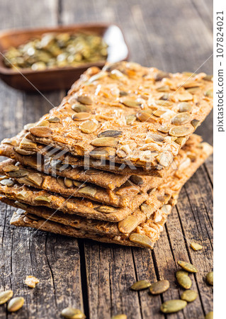 Knackebrot with pumpkin seeds. Wholegrain crispbread on wooden table. 107824021