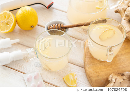 Natural cold remedies concept - ginger tea and ingredients, drugs, thermometer Natural cold remedies concept - ginger tea and ingredients, drugs, thermometer 107824708