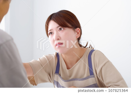 A young woman wearing an apron expressing anger 107825364