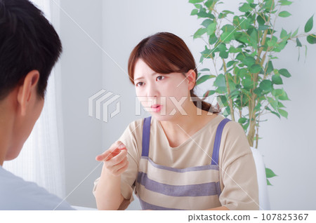 A young woman wearing an apron expressing anger 107825367