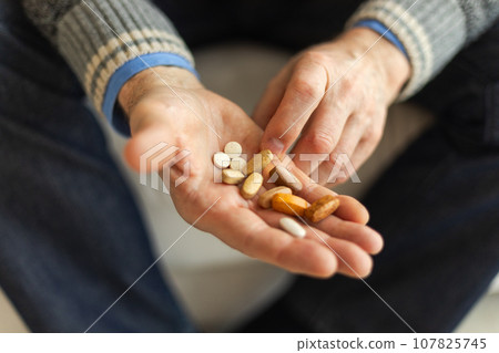 Hands with pills. Senior man hands holding medical pill. Mature old senior grandfather taking medication cure pills vitamin. Age prescription medicine healthcare therapy concept Hands with pills. Senior man hands holding medical pill. Mature old senior grandfather taking medication cure pills vitamin. Age prescription medicine healthcare therapy concept 107825745