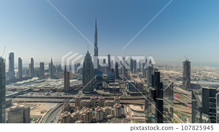 Panorama showing aerial view of tallest towers in Dubai Downtown skyline and highway timelapse. 107825945