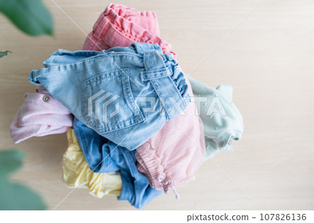 Selection of fresh unfolded laundry in white basket on wood table Selection of fresh unfolded laundry in white basket on wood table 107826136