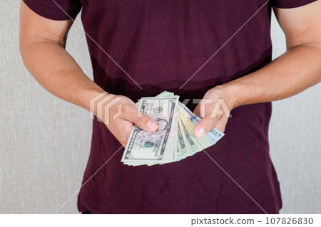 man holds a wad of dollars in his hands. US Dollars man holds a wad of dollars in his hands. US Dollars 107826830
