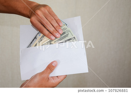 Money in white envelope in the hands of a man. Dollars, a wad of dollars. Money in white envelope in the hands of a man. Dollars, a wad of dollars. 107826881