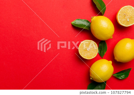 Many fresh ripe lemons with green leaves on colored background, top view, space for text Many fresh ripe lemons with green leaves on colored background, top view, space for text 107827794