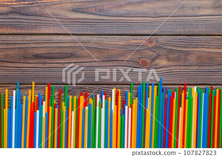 Heap of colorful plastic drinking straws on Colored background, flat lay. Copy Space for text Heap of colorful plastic drinking straws on Colored background, flat lay. Copy Space for text 107827823