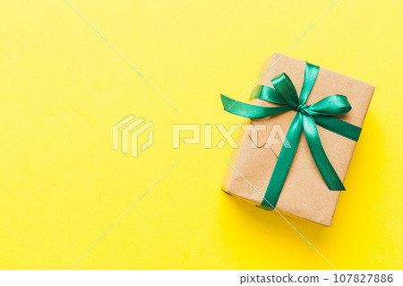 wrapped christmas or other holiday handmade present in paper with colored ribbon. Present box, decoration of gift on colourfull table, top view with copy space wrapped christmas or other holiday handmade present in paper with colored ribbon. Present box, decoration of gift on colourfull table, top view with copy space 107827886
