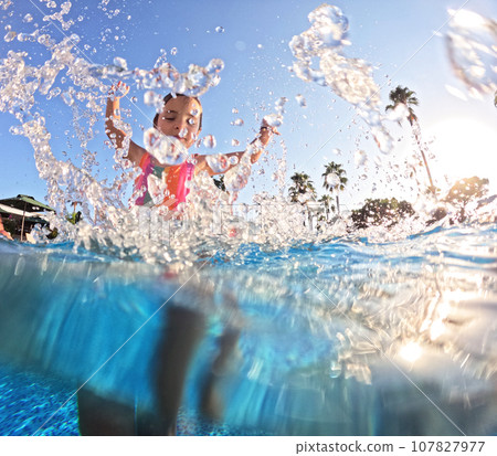 Little girl splashing water in the pool, playing in the water, having fun. Beach resort vacation by sea. Winter or summer seaside holiday. Little girl splashing water in the pool, playing in the water, having fun. Beach resort vacation by sea. Winter or summer seaside holiday. 107827977