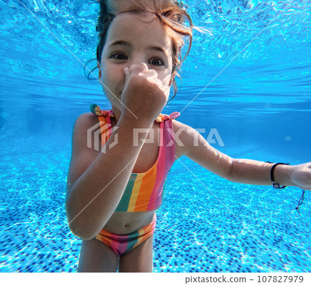 Girl diving underwater in the pool during summer vacation, playing in the water. Winter or summer seaside holiday. Underwater photography. Girl diving underwater in the pool during summer vacation, playing in the water. Winter or summer seaside holiday. Underwater photography. 107827979