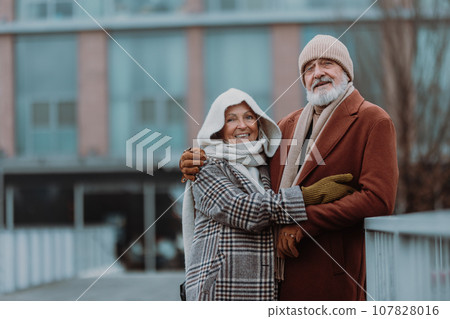Elegant senior couple walking near the river, during cold winter day. 107828016