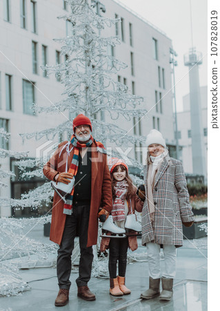 Seniors with their granddaughter at outdoor ice skating rink during winter day. Seniors with their granddaughter at outdoor ice skating rink during winter day. 107828019