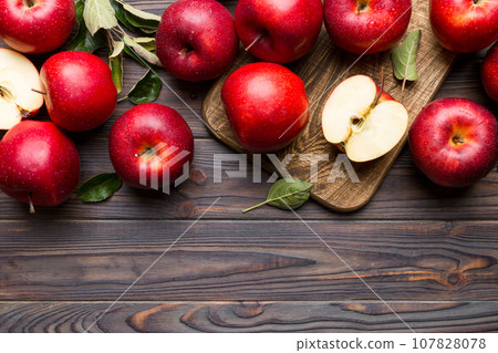 Fresh red apples with green leaves on table. cutting board with knife. Top view 107828078