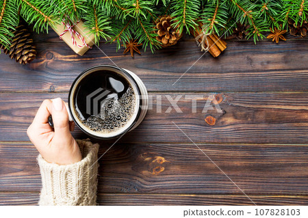 Woman hand hold Mug of coffee on black wooden christmas background. top view, copy space Woman hand hold Mug of coffee on black wooden christmas background. top view, copy space 107828103