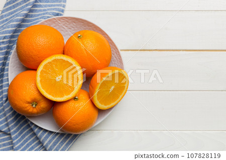 Flat lay of Fresh orange fruit with sliced in plate on Colored background. Top view with copy space Flat lay of Fresh orange fruit with sliced in plate on Colored background. Top view with copy space 107828119