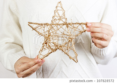 Hands of young woman holding a golden star for Christmas decoration Hands of young woman holding a golden star for Christmas decoration 107828572