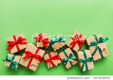 wrapped christmas or other holiday handmade present in paper with colored ribbon. Present box, decoration of gift on colourfull table, top view with copy space 107828602