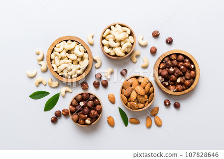 Assortment of nuts in wooden bowl on colored table. Cashew, hazelnuts, walnuts, almonds. Mix of nuts Top view with copy space Assortment of nuts in wooden bowl on colored table. Cashew, hazelnuts, walnuts, almonds. Mix of nuts Top view with copy space 107828646