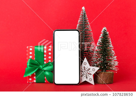 Digital phone mock up with rustic Christmas decorations for app presentation with empty space for you design. Christmas online shopping concept. Tablet with copy space on colored background Digital phone mock up with rustic Christmas decorations for app presentation with empty space for you design. Christmas online shopping concept. Tablet with copy space on colored background 107828650