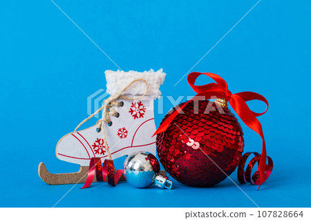 Christmas ball with skates on colored background. decoration bauble with ribbon bow with copy space Christmas ball with skates on colored background. decoration bauble with ribbon bow with copy space 107828664