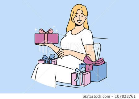 Pregnant woman with gift box strokes belly and looks at screen in anticipation of birth of baby 107828761