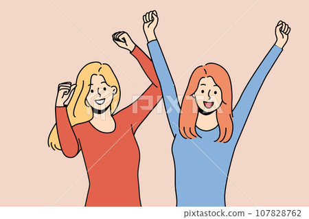 Two women triumphantly raise hands up celebrating successful completion of college 107828762