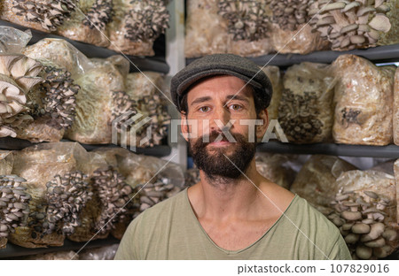Young man - owner of domestic mushroom greenhouse. 107829016