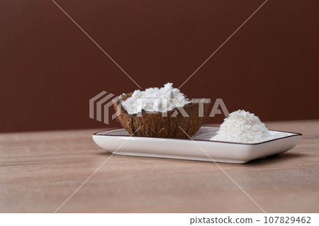 Half a coconut with a handful of white coconut powder for making protein shakes, healthy drinks. Half a coconut with a handful of white coconut powder for making protein shakes, healthy drinks. 107829462