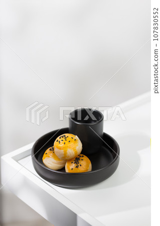 Chinese pastry and hot tea in a black ceramic cup. 107830552