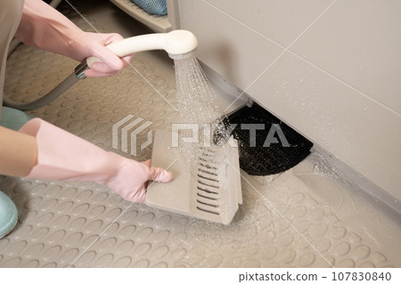 Hands of a woman cleaning the drain in the bathroom while taking a shower 107830840